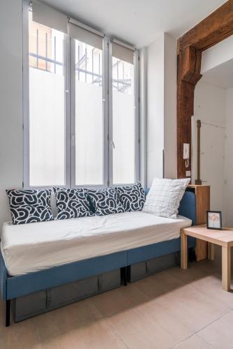 - un lit dans une chambre avec 2 fenêtres dans l'établissement Apart Merryland Paris Châtelet, à Paris