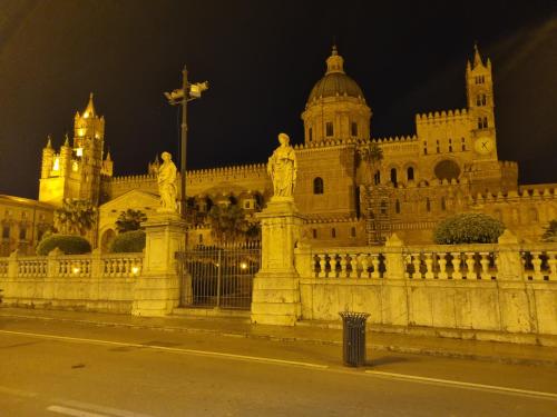 a building with statues in front of it at night at Onda blu in Carini