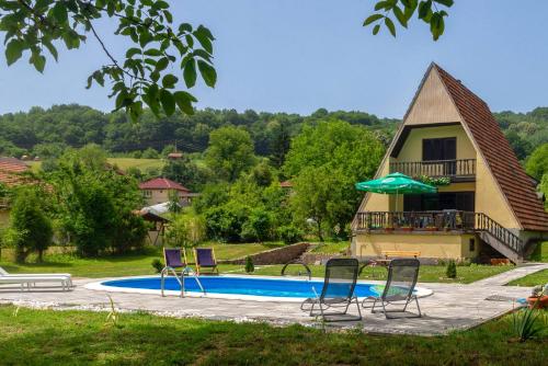 a swimming pool with chairs and a house at Vikendica Solitudo House Tuzla in Crno Blato