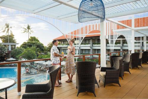 Twee vrouwen staan op het balkon van een resort met een zwembad. bij Bali Dynasty Resort in Kuta