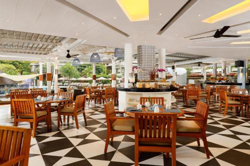 een restaurant met tafels en stoelen en een dambord vloer bij Bali Dynasty Resort in Kuta