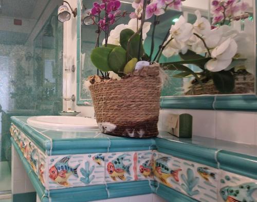 a bathroom with a sink and a vase with flowers at Albergo La Conca Azzurra in Conca dei Marini