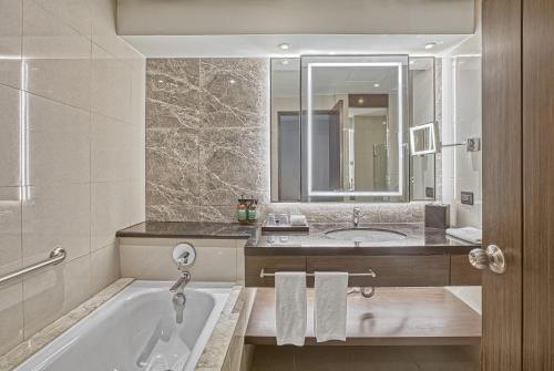 a bathroom with a tub and a sink and a mirror at Holiday Inn & Suites Manila Galleria by IHG in Manila