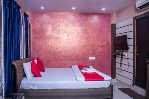 a bedroom with a bed with red pillows at Babul Hotel in Kolkata