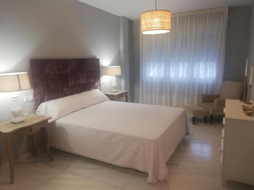 a bedroom with a white bed and a living room at Areos in Pobra do Caramiñal