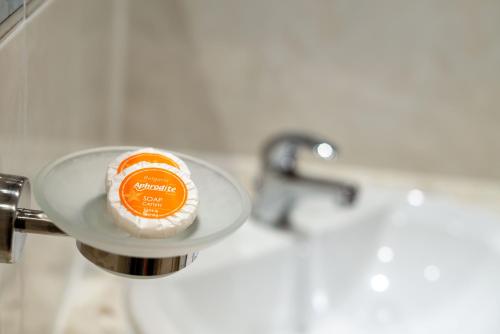 a bathroom sink with a plate with an orange on it at Aphrodite Beach Hotel in Nesebar