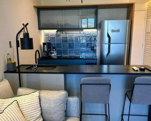 cocina con nevera y barra con sillas en Beachfront Studio,, en Río de Janeiro