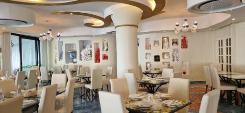 a dining room with tables and chairs and paintings on the walls at Albergo La Conca Azzurra in Conca dei Marini
