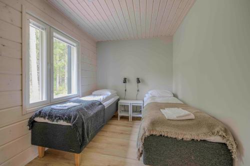 two beds in a room with a window at Luksushuvila Villa Helmi in Himos