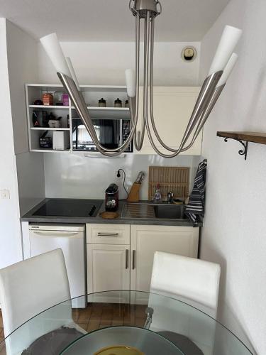 une cuisine avec une table en verre et deux chaises blanches dans l'établissement Au centre ville de la Grande Motte, à 200m de la plage N68, à La Grande Motte