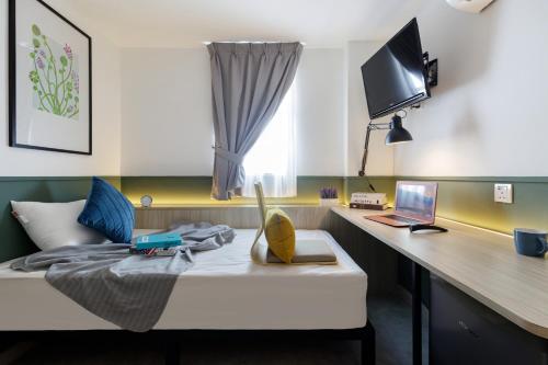 a room with a bed with a desk and a laptop at Upstairs Downstairs CoLiving Bukit Bintang in Kuala Lumpur