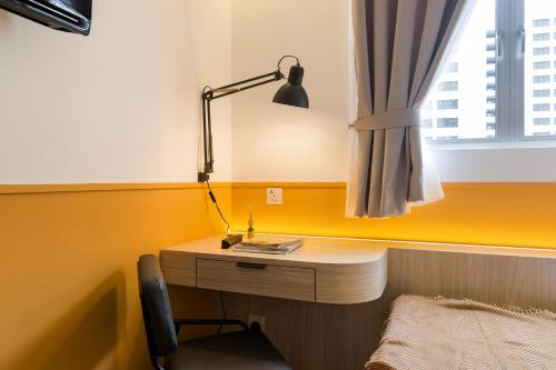 a desk with a lamp and a chair next to a window at Upstairs Downstairs CoLiving Bukit Bintang in Kuala Lumpur