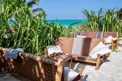two chairs on a beach with the ocean in the background at Mahali Zanzibar in Paje