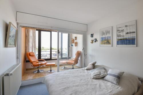 - une chambre avec un lit et deux chaises et un balcon dans l'établissement Le Balcon sur Juno - A 10min à pied de la plage, à Courseulles-sur-Mer