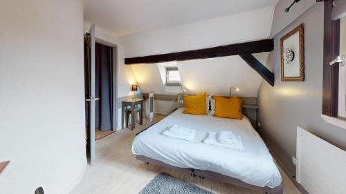 - une petite chambre avec un lit et des oreillers jaunes dans l'établissement La Grande Ourse, à Colmar