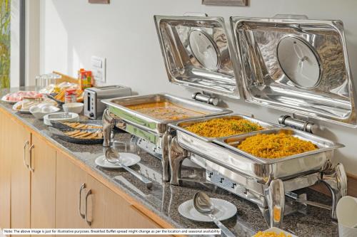 a kitchen counter with several trays of food at Treebo Premium Nestlay Rooms Nungambakkam in Chennai