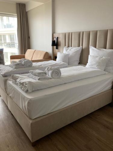 un grande letto con lenzuola bianche e cuscini sopra di Apartament Morski Widok a Jarosławiec