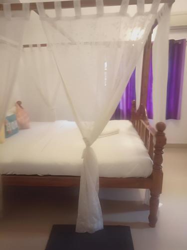 a bedroom with a bed with a mosquito net at Ronne's Casa De Piscina Privada 3BHK VILLA in Verla