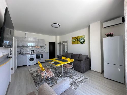 a living room with a couch and a table in a kitchen at Raduga West 'Coco' Apartment in Koshkolʼ