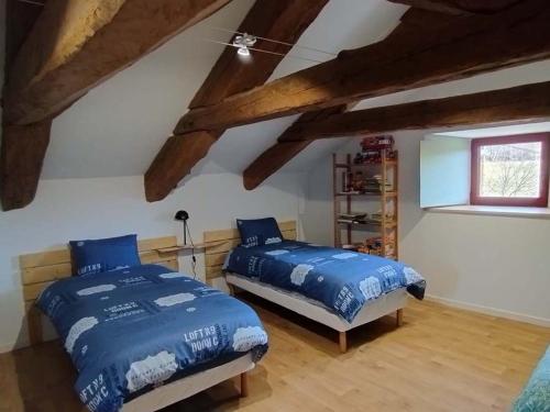Un dormitorio con dos camas y una ventana. en La Ferme d'Adèle, en Tence