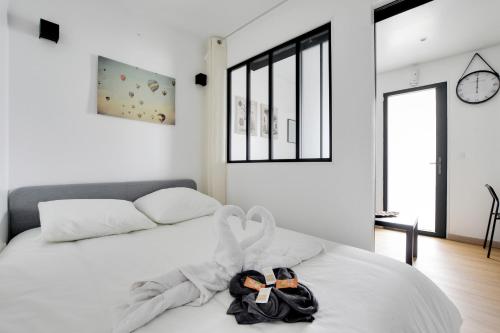 une chambre blanche avec un lit avec des serviettes dessus dans l'établissement Charming 1 Bedroom with Sauna - Romainville 2, à Bagnolet