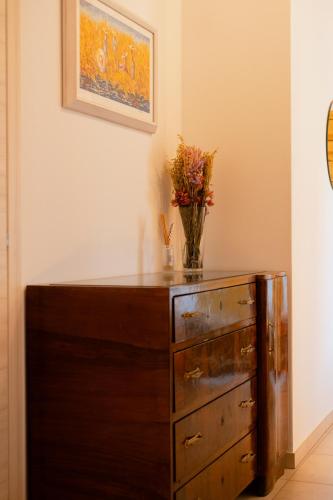 a vase of flowers sitting on top of a wooden dresser at Fattoria Cerqua Rooms and more in Montegranaro