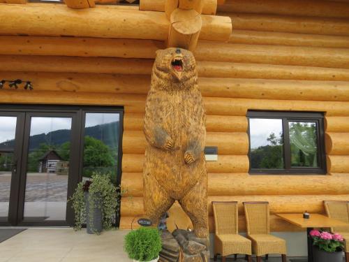 a statue of a bear standing in front of a log cabin at Bucovina Exclusiv in Vama