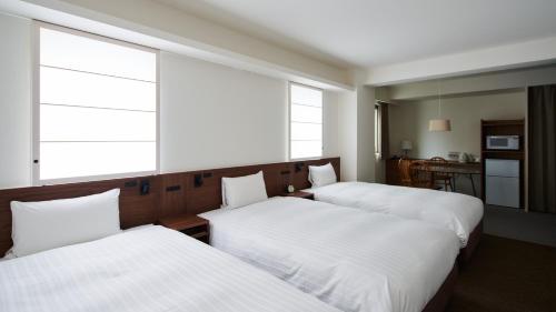 two beds in a room with two windows at Shin-Osaka Station Hotel in Osaka