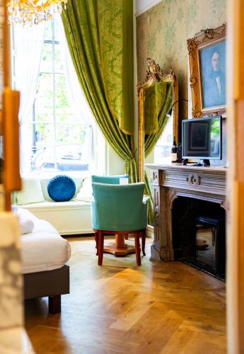 a living room with a fireplace and a green chair at Boutique Hotel Museumkwartier in Utrecht