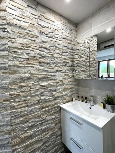 une salle de bain avec un lavabo et un mur en pierre dans l'établissement coccon, tv, wifi, à Albertville