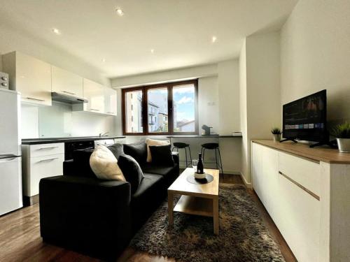 un salon avec un canapé noir et une table dans l'établissement coccon, tv, wifi, à Albertville