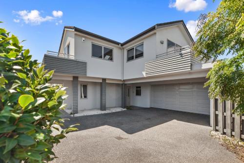 a large white house with a garage at Endless Summer - Mount Maunganui Holiday Home in Matapihi
