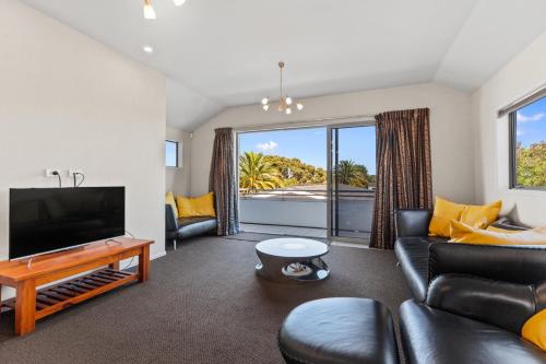 a living room with a couch and a television at Endless Summer - Mount Maunganui Holiday Home in Matapihi