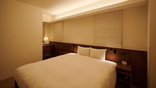 a bedroom with a white bed and a desk at Shin-Osaka Station Hotel in Osaka