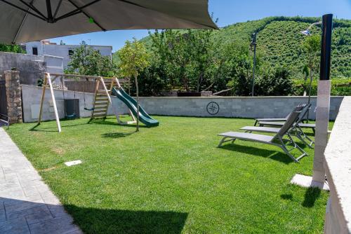 a backyard with a swing set and an umbrella at La Stella dei venti in Vico Equense