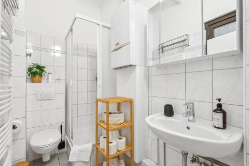 a white bathroom with a sink and a toilet at FABYLOUS Homes City Apartment I Gruppen I Waschtrockner I Balkon I belebte Lage in Wiesbaden