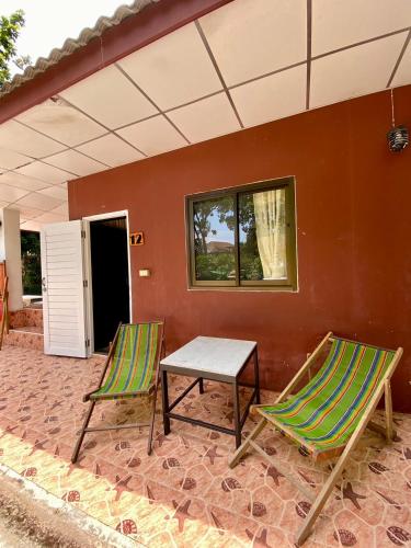 two chairs and a table on a patio at พลาบุรี รีสอร์ท 012 in Ban Phala