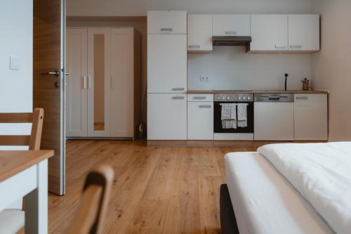 a kitchen with white cabinets and a bed in a room at Kalkalpen Apartments in Spital am Pyhrn