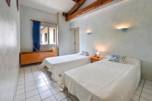 a bedroom with two beds and a window at Maison plain pied mitoyenne avec piscine partagée et terrain arboré in Brens