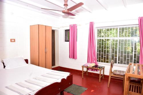 a bedroom with a bed and a window with pink curtains at Ocean Green Kerala in Kannur