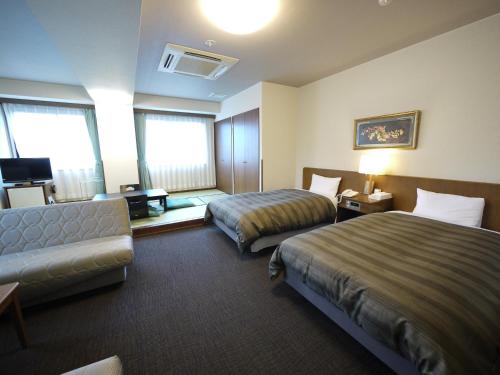 a hotel room with two beds and a couch at Route Inn Grantia Hidatakayama in Takayama