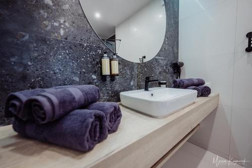 a bathroom with a sink and a mirror and purple towels at Cristal in Ustka