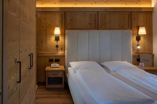 a bedroom with a large bed with two pillows at Belvedere Dolomites Flower Hotel in Moena