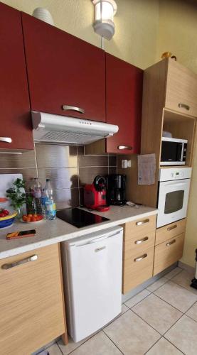 une cuisine avec des armoires rouges et un réfrigérateur blanc dans l'établissement Appartement cap dagde, au Cap d'Agde