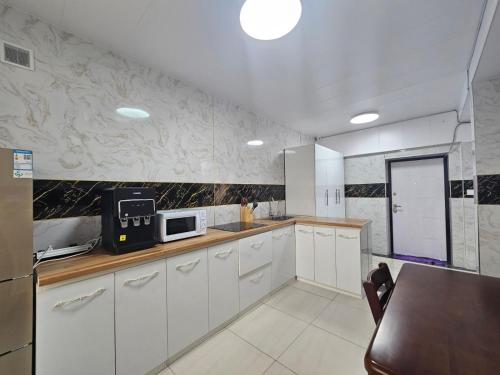 a kitchen with white cabinets and a counter with a microwave at Etuga Guesthouse, Close to Sukhbaatar Square in Ulaanbaatar
