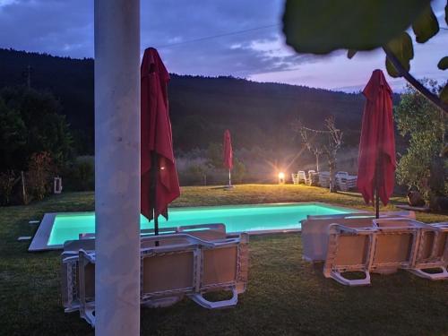 a swimming pool with a red umbrella and tables and chairs at Sotam Country House EN342 in Góis