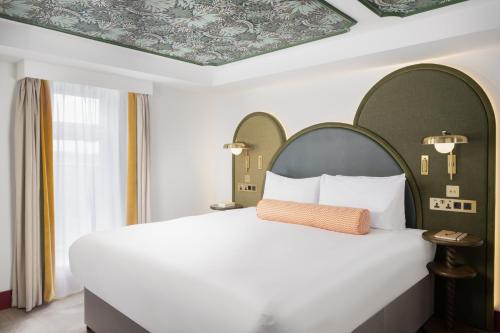 a bedroom with a large white bed and a ceiling at The Welbeck Hotel by IHG in London