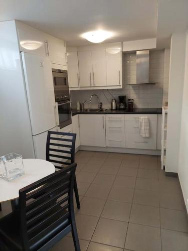 a kitchen with white cabinets and a table and chairs at Lägenhet på landet nära stan in Jonsered