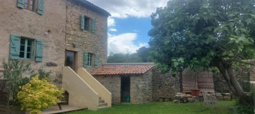 a stone house with a staircase next to a building at Gîte le Fort in Vesseaux