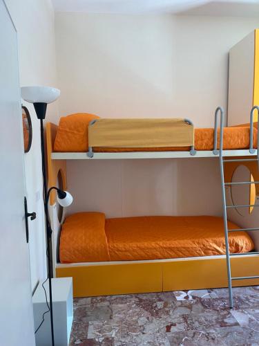 two bunk beds in a room with orange sheets at Casa Giovenza in Porto Azzurro